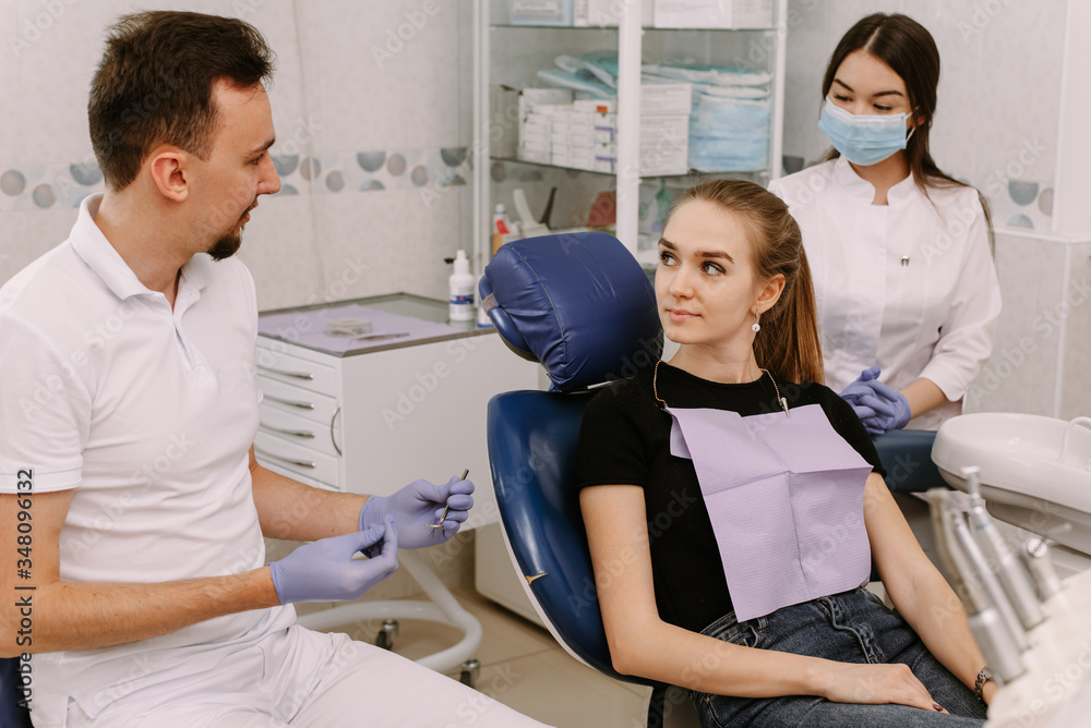 Fototapeta premium Dentist talking to a patient. Nearby is the dentist's ass. Reception in the dentist s office and dental treatment