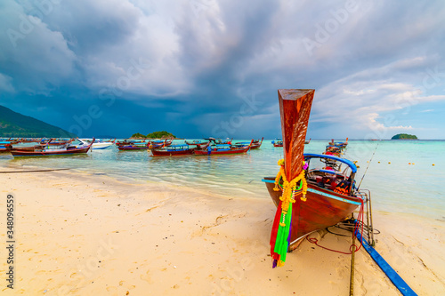 Small harbor with long tail boats at Ko Lipe island, Thailand, shortly before tropical storm. Big and heavy dark clouds above sea. Detail of wooden boats typical for Thailand. © Martin
