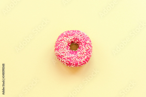 Pink donut on yellow background, top view