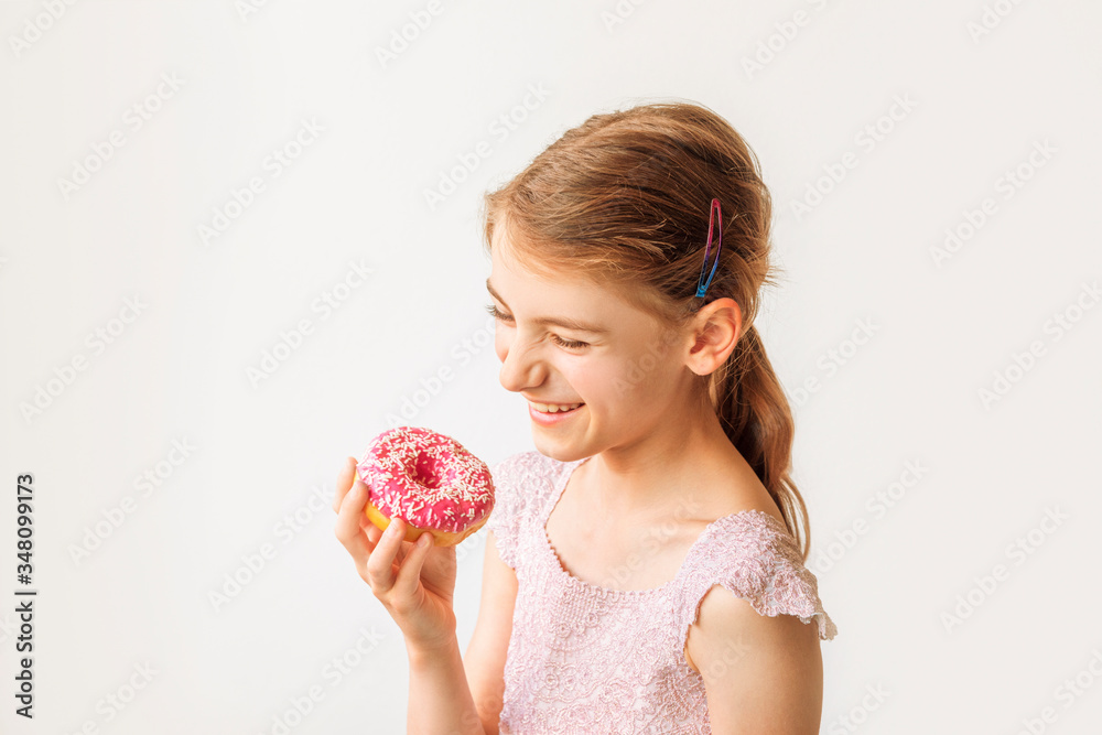 Cute blonde little girl eating pink donut and smiling. Junk food concept. Cute blonde little girl eating pink donut and smiling. Junk food concept.