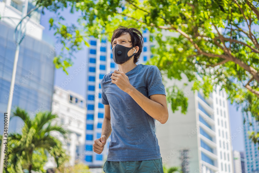 Man runner wearing medical mask. Running in the city against the backdrop of the city. Coronavirus pandemic Covid-19. Sport, Active life in quarantine surgical sterilizing face mask protection