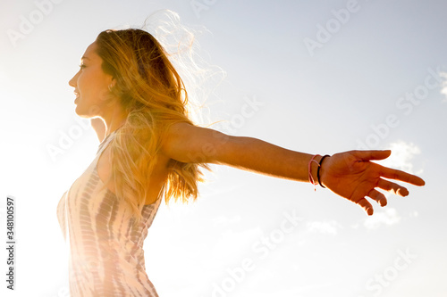 Happiness and freedom joy concept with young beautiful caucasian girl open arms and enjoy the sun - people in outdoor free activity - blonde beautiful woman with bright sky background