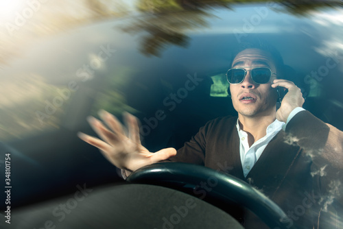 Фотография Driver man wearing sunglasses while talking on the mobile phone