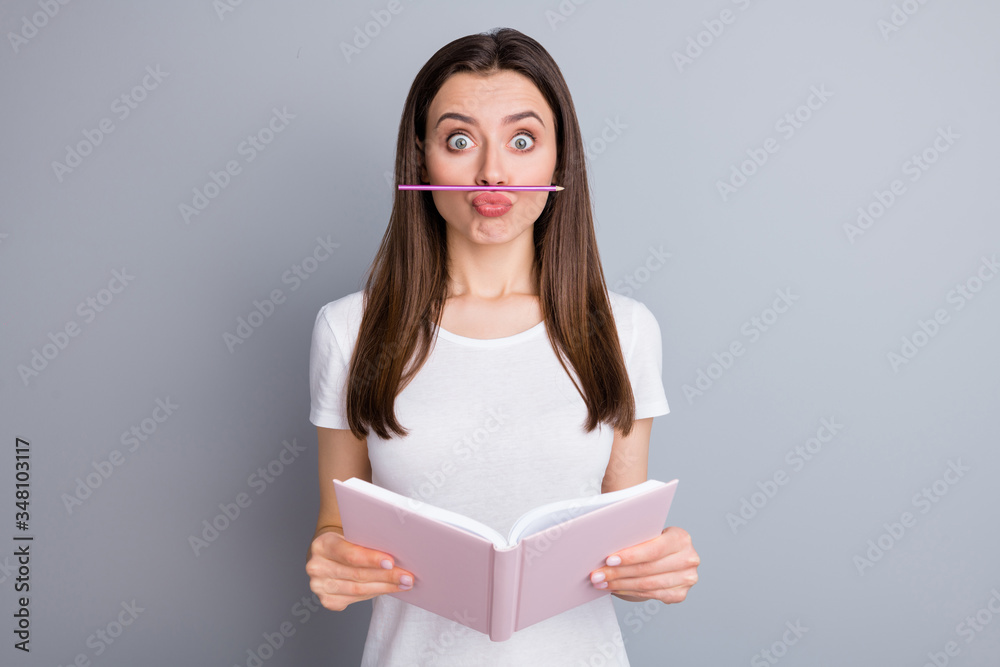 Portrait of funny playful childish girl put nose pencil have distance learning break want joke hold copybook wear stylish clothes isolated over gray color background Portrait of funny playful childish girl put nose pencil have distance learning break want joke hold copybook wear stylish clothes isolated over gray color background