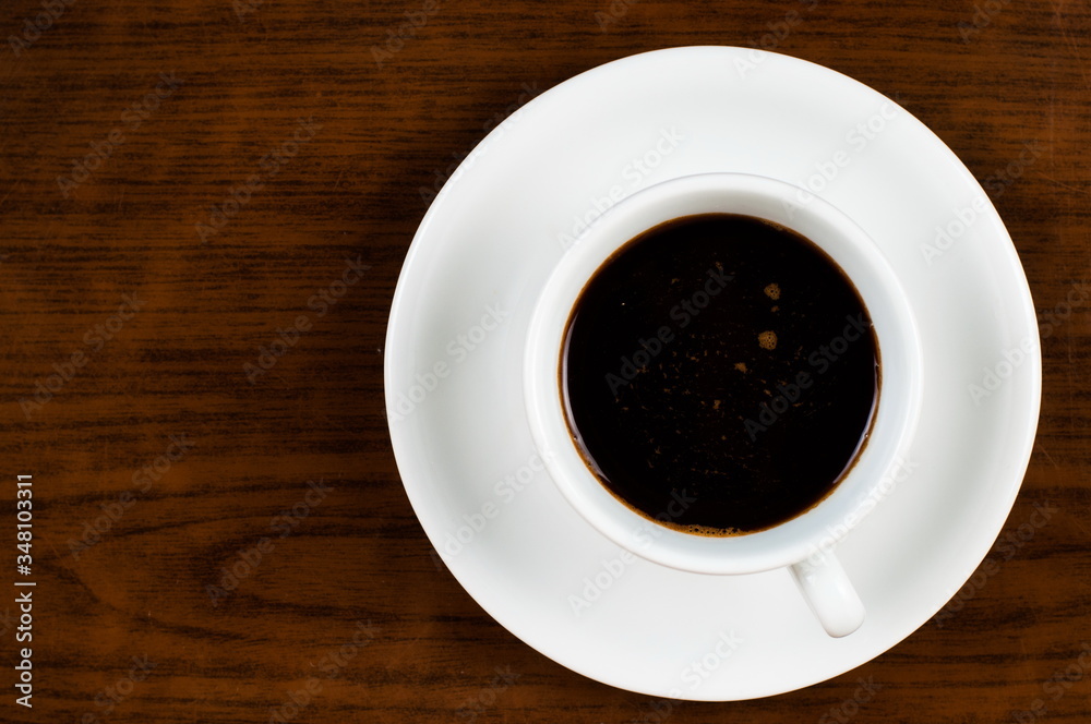 Obraz premium White coffee cup and coffee beans on a wooden table.Coffee time