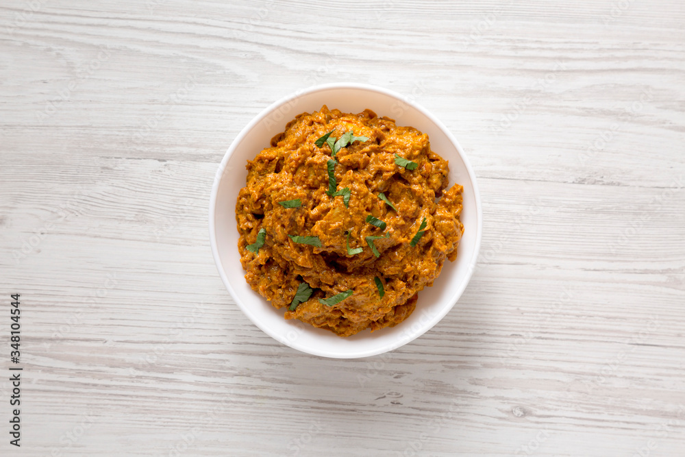 Homemade Chicken Tikka Masala in a white bowl on a white wooden surface, top view. Flat lay, overhead, from above. Homemade Chicken Tikka Masala in a white bowl on a white wooden surface, top view. Flat lay, overhead, from above.