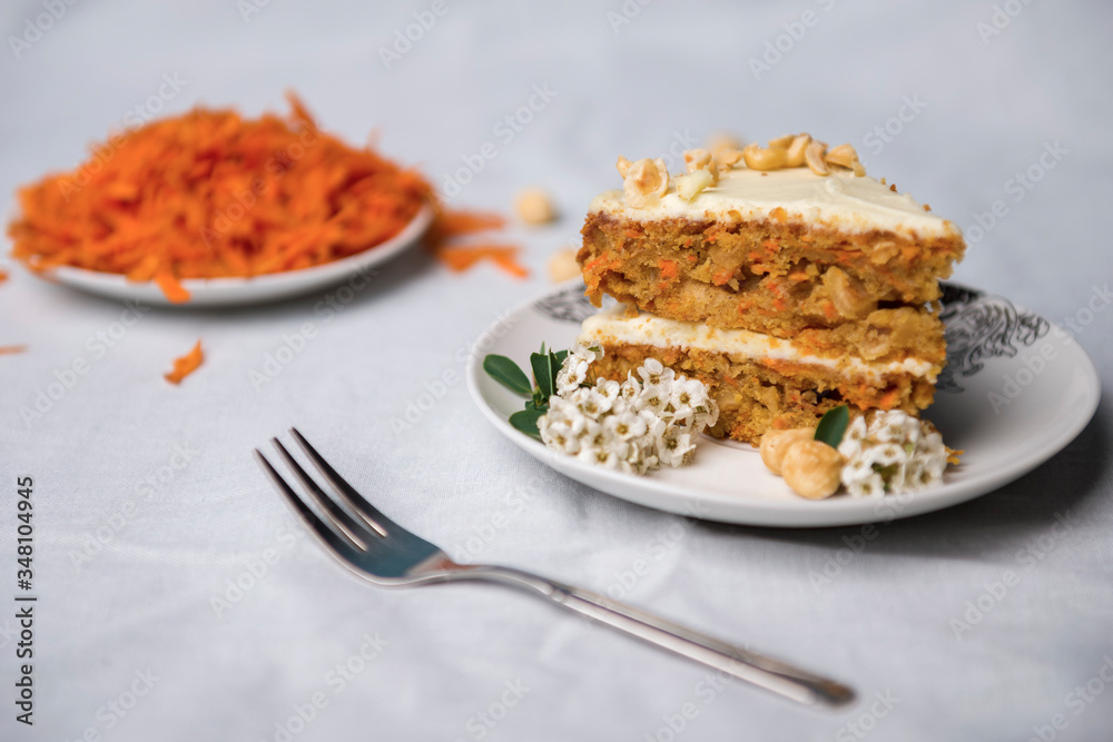 Piece of carrot decorated with white flowers and grated carrots on the background