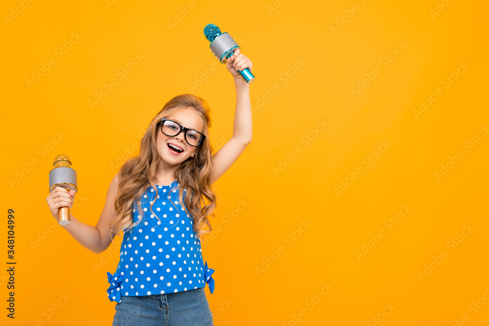 A little girl with glasses with a microphone is interviewed, the picture is isolated on yellow background A little girl with glasses with a microphone is interviewed, the picture is isolated on yellow background