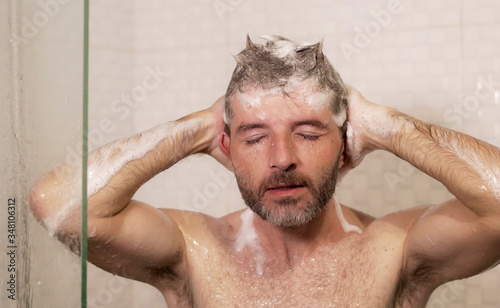 morning shower - lifestyle portrait of young attractive and happy man with beard taking a shower at home washing his hair with shampoo enjoying cheerful