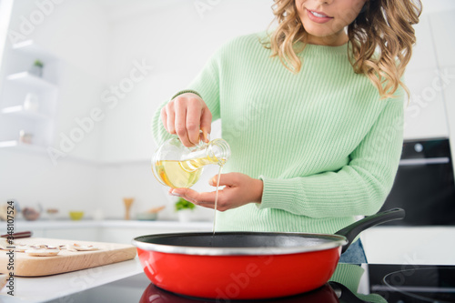 Cropped photo of beautiful housewife hold olive oil pouring hot frying pan enjoy hobby morning cooking tasty dinner family stand bright light kitchen indoors casual clothing © deagreez