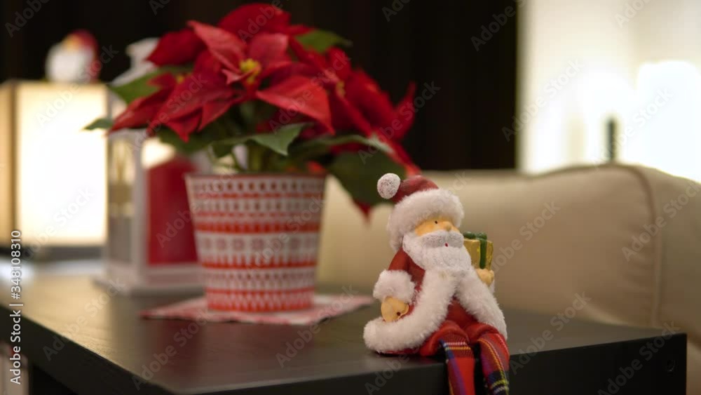A Santa Claus figure sits on the edge of a table in a Christmas-decorated apartment A Santa Claus figure sits on the edge of a table in a Christmas-decorated apartment
