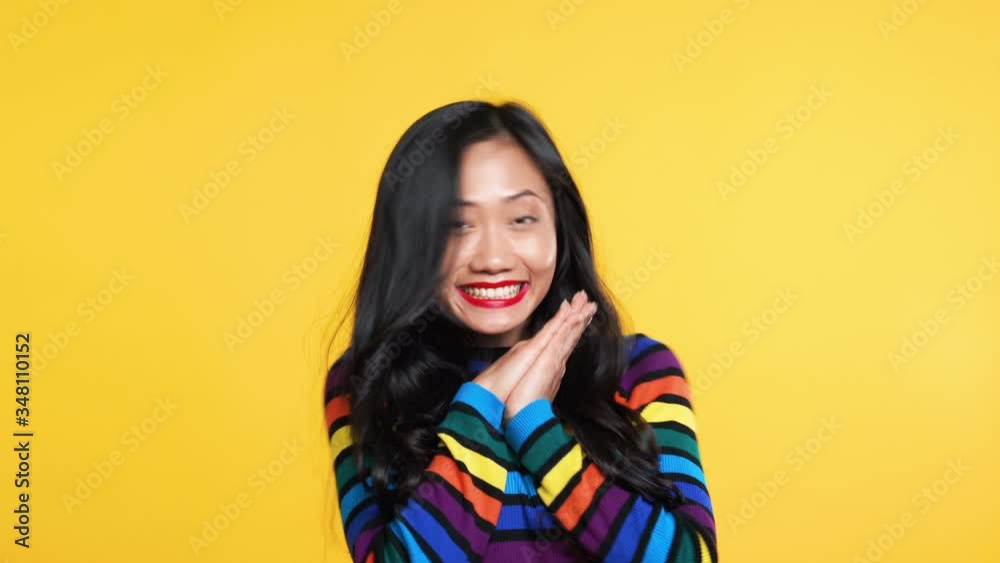 Happy asian woman rejoice and clapping over yellow background Happy asian woman rejoice and clapping over yellow background