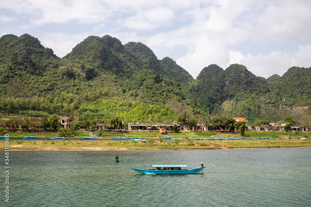 Song Son River with wooden boat on the water on the background of the mountains in Phong Nha, Vietnam