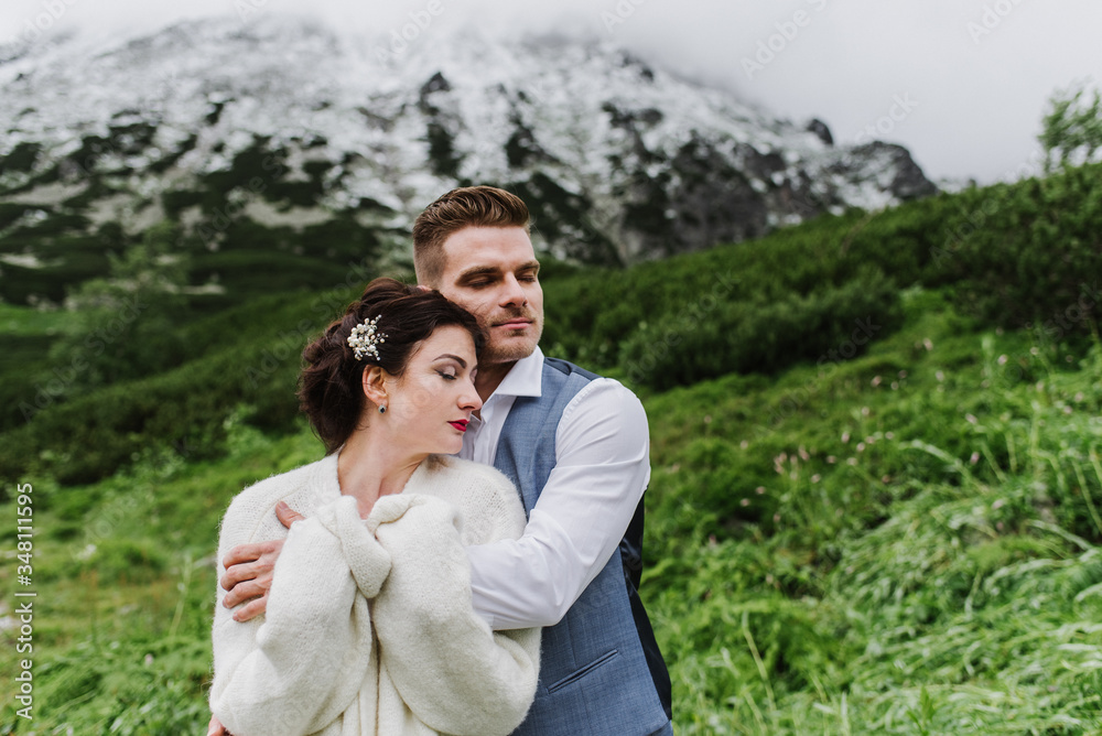 Beautiful bride and groom hug and kiss in the mountains.