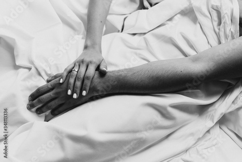 Hands of man and woman close-up in bed.