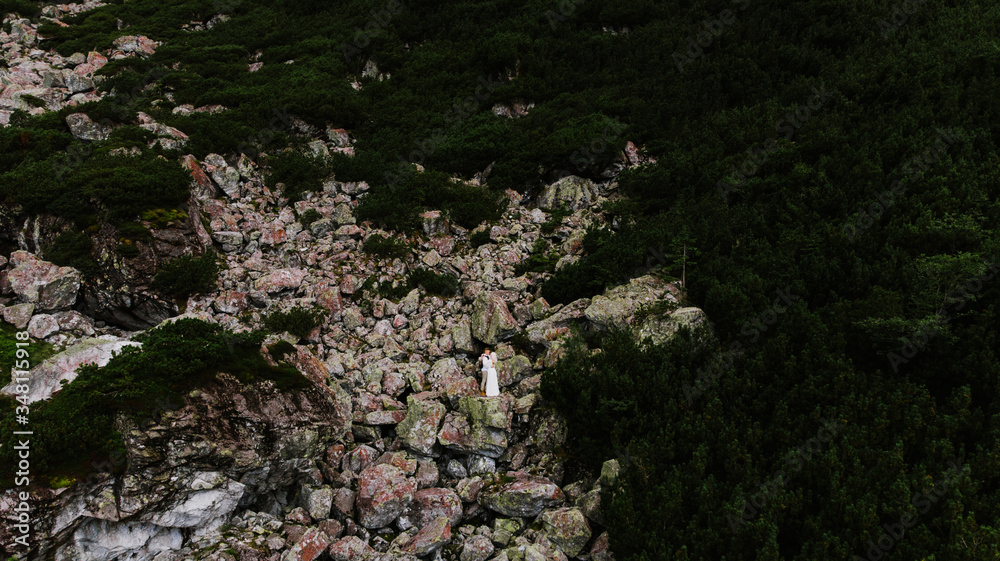 Beautiful bride in a boho style dress and groom hug and kiss in the mountains. Wedding photo shoot in the mountains.