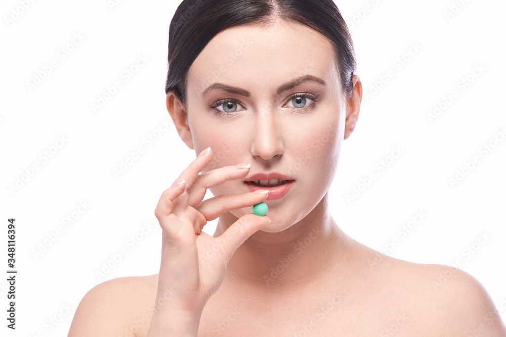 Girl holding a pill. Vitamins concept. Beautiful portrait on white background. Medicine home routine. Female morning supplement. Meds anti allergy drug Girl holding a pill. Vitamins concept. Beautiful portrait on white background. Medicine home routine. Female morning supplement. Meds anti allergy drug