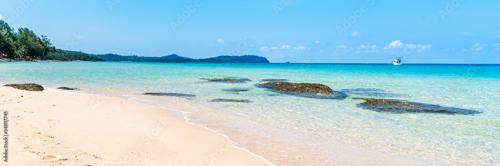 Fototapeta premium Tropical beautiful beach sand and sea with wave reaching shore with blue sky and white clouds, summer travel or vacation concept