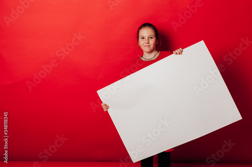 Schoolgirl's girl holds sign for inscriptions on red background photo