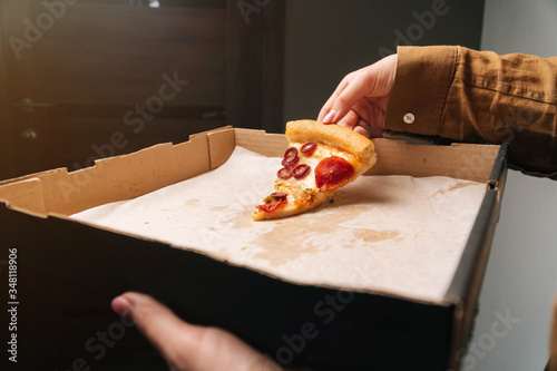 Obraz na płótnie Girl picks up last piece of pepperoni pizza from box closeup