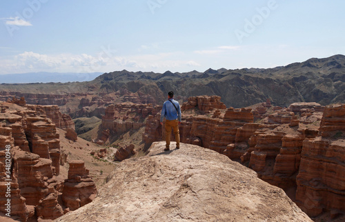 Man standing on a rock overseeing the magnificent landscape of Charyn Canyon, Kazakhstan