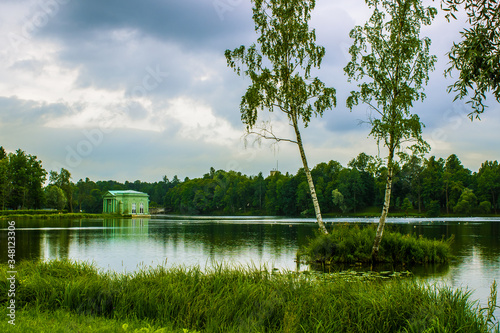 Summer landscape. The lake among the park. Trees are reflected in the lake.
