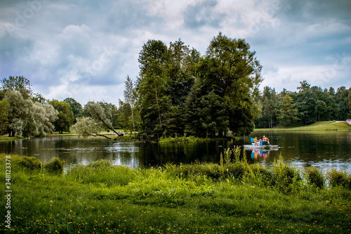 Summer landscape. The lake among the park. People are relaxing on boats.