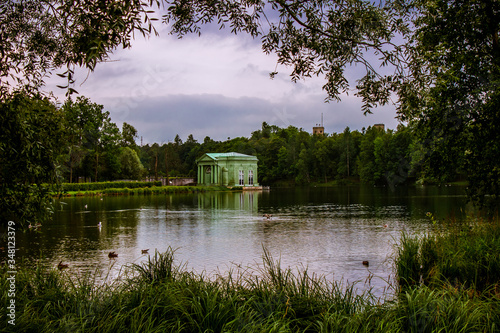 Summer landscape. The lake among the park. Trees are reflected in the lake.