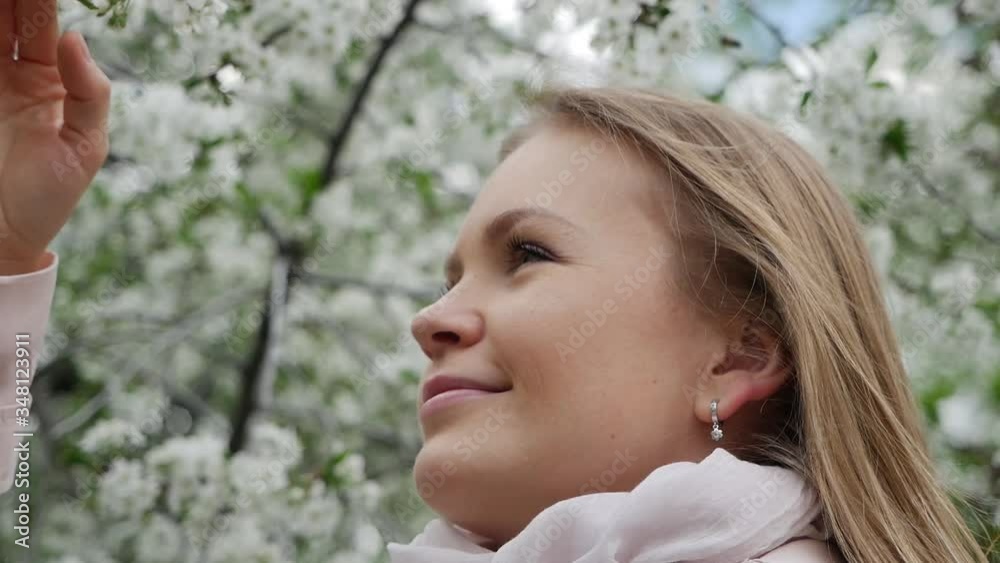 Beautiful attractive pretty girl in a good mood admires and sniffs a flowering tree. Close-up. Beautiful attractive pretty girl in a good mood admires and sniffs a flowering tree. Close-up.