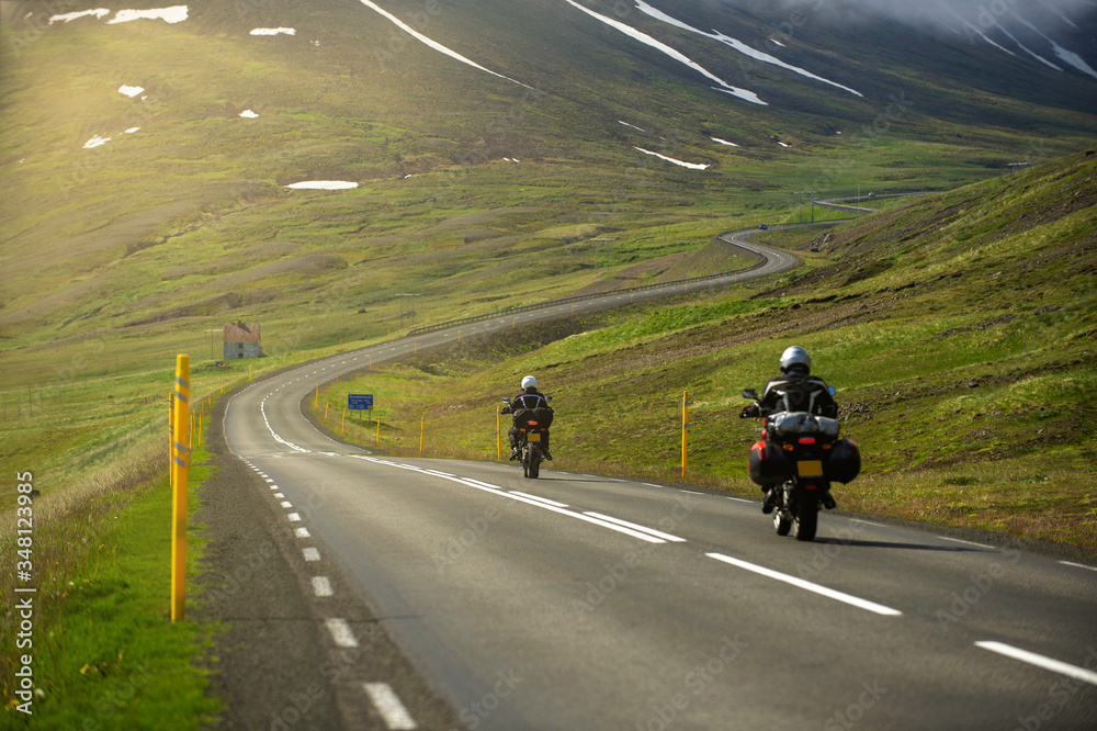 Two motorcycles running on the hill road Head to the great mountain and there is a winding road. In the summer season, bikers like to drive for group trips in Iceland.