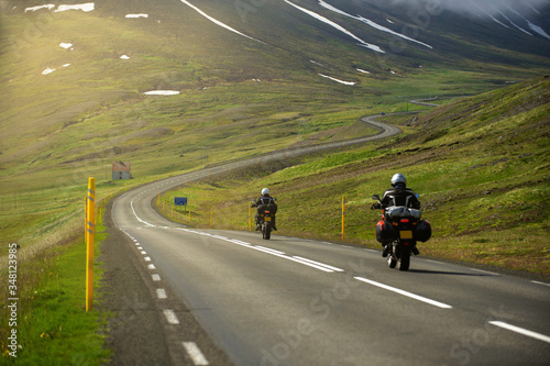 Two motorcycles running on the hill road Head to the great mountain and there is a winding road. In the summer season  bikers like to drive for group trips in Iceland.