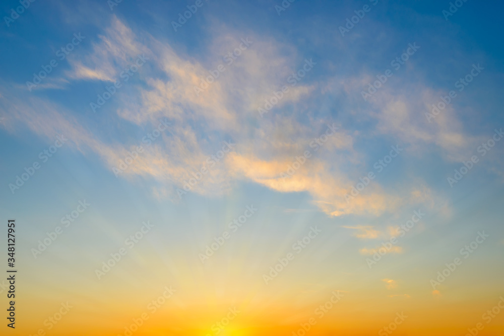 Summer sunrise sky with sunbeams and few golden translucent clouds. Beautiful dawn skyscape. Clear paradise sky at early morning. Calm blue heaven.