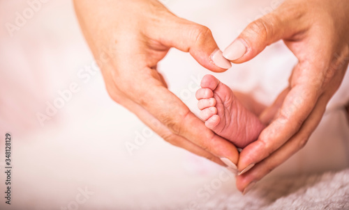 Legs newborn baby hands hug mother, forming a heart. Symbolizes love, unity, caring, tender to the baby. New family concept.