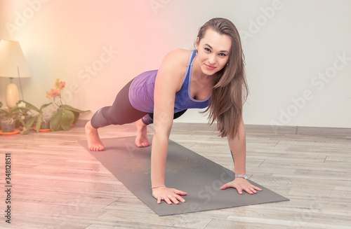 Beautiful young woman doing plank at home