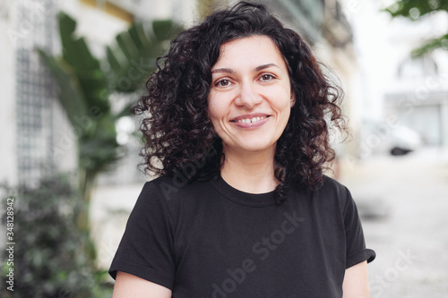 Young woman with curly hair and diastema with a happy smile, outside on a street © Надежда Филатова