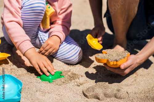 Happy father and daughter play in sand on the beach.