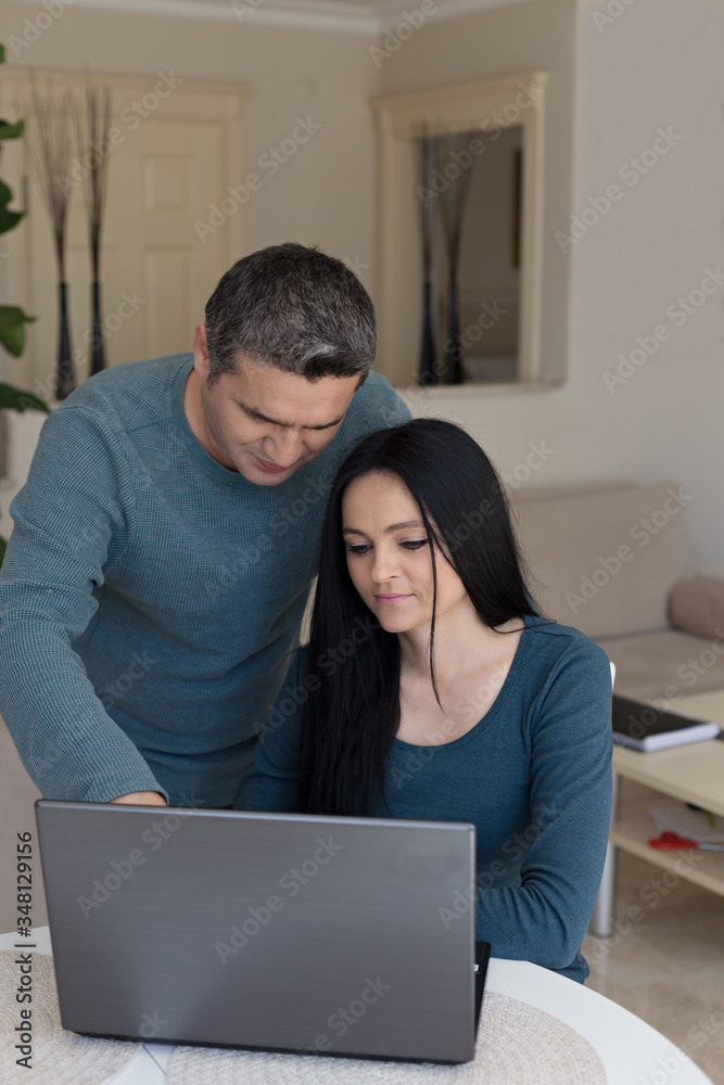 Couple in matching outfites working from home using black laptop Couple in matching outfites working from home using black laptop