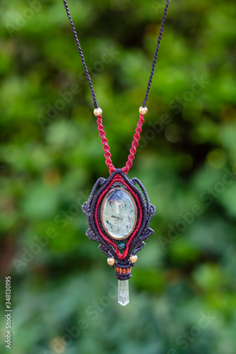 Macrame mineral stone necklace on natural green bokeh background