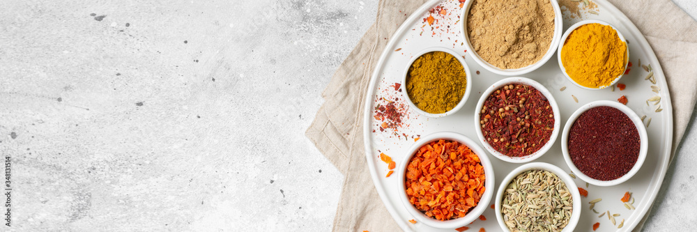 Spices and condiments in white cups and spoons on a light gray table.Fennel, sumac, Curry in white masks. Spices close-up with space for text. The view from the top. Banner Spices and condiments in white cups and spoons on a light gray table.Fennel, sumac, Curry in white masks. Spices close-up with space for text. The view from the top. Banner