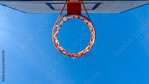 Under Basketball hoop with clear blue sky