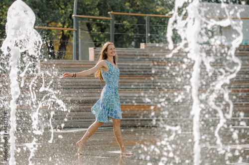 Girl in a blue dress having fun among the fountains