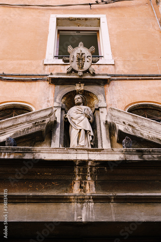 Close-ups of building facades in Venice, Italy. An ancient stone statue above the door.