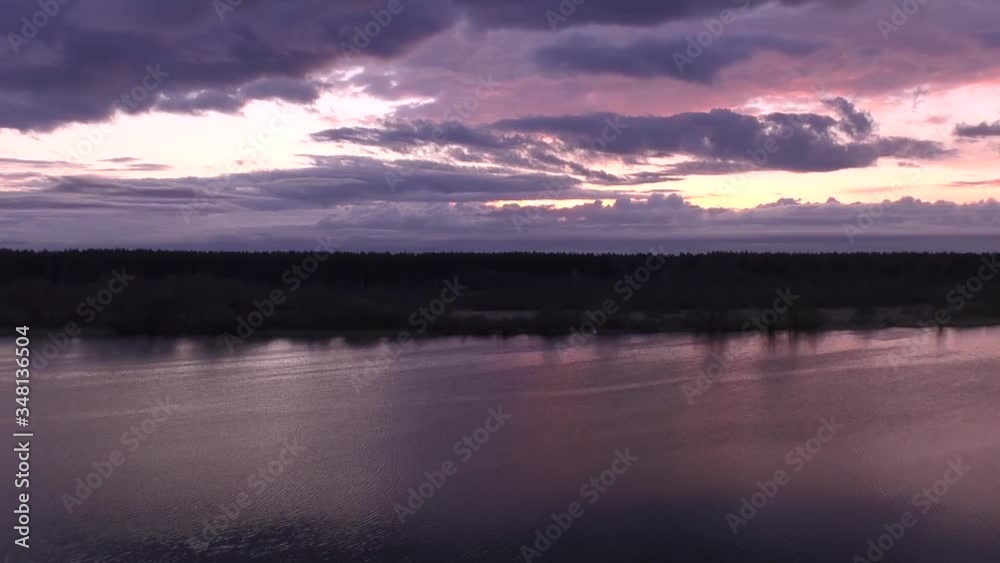 Lilac landscape.Movement of purple clouds over the violet river.The black silhouette of the forest separates the water expanse and the low sky reflected on the surface in a light haze at dawn.Russia Lilac landscape.Movement of purple clouds over the violet river.The black silhouette of the forest separates the water expanse and the low sky reflected on the surface in a light haze at dawn.Russia