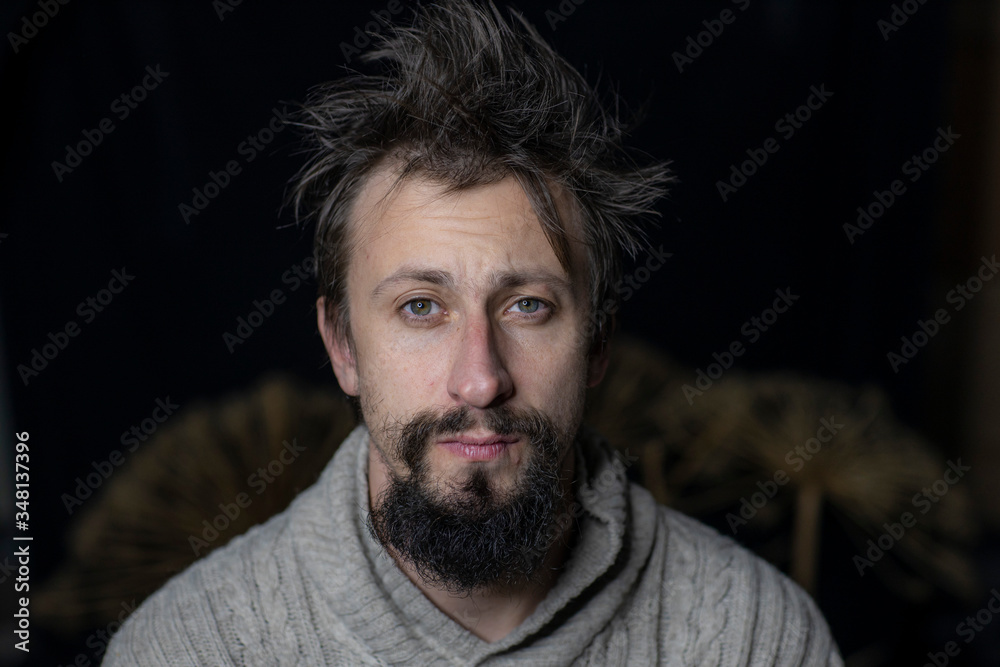 Fototapeta premium a young man with a beard rumpled appearance in a sweater. The fight against alcoholism