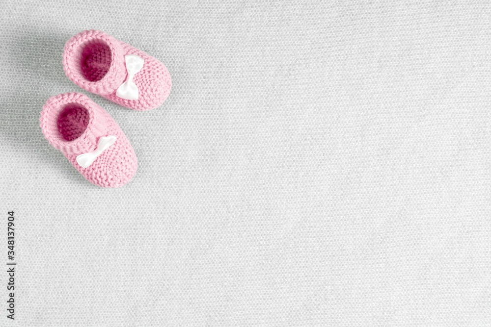 Pink toddler shoes on gray knitted blanket. Baby booties. Flat lay, top view, copy space