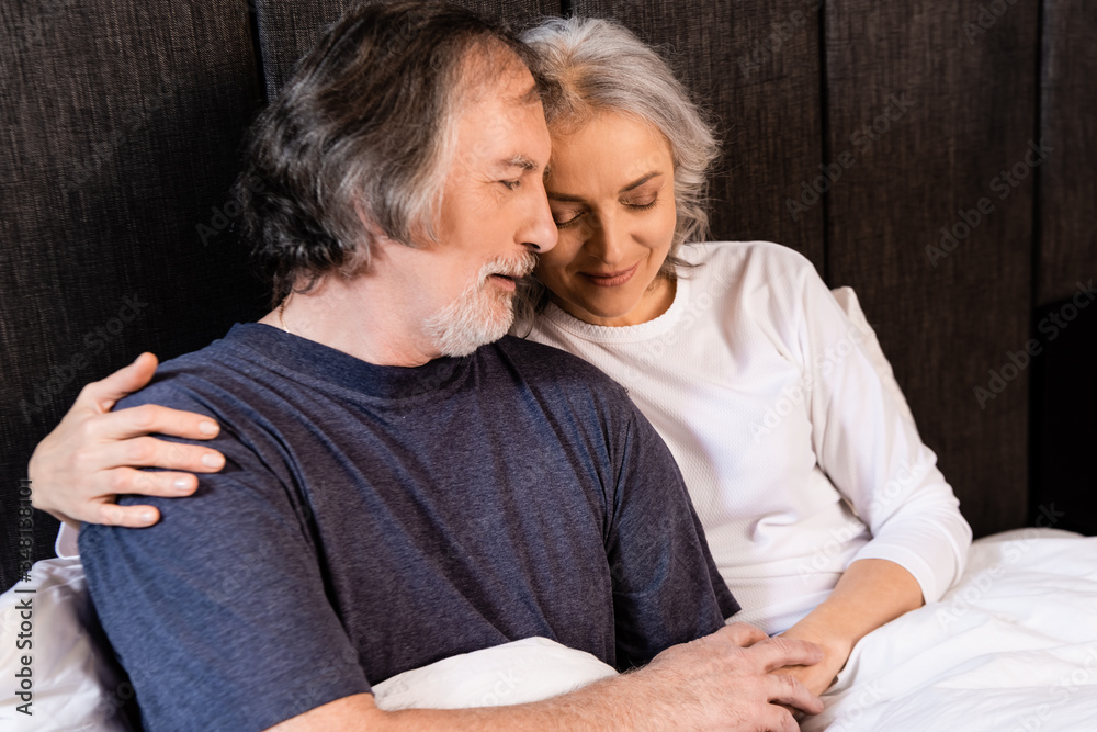 happy mature couple hugging and smiling in bed happy mature couple hugging and smiling in bed
