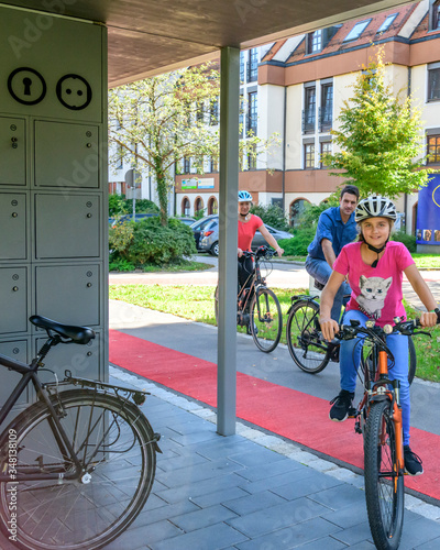 Gutgelaunte Familie nutzt ein vorbildliches Fahrrad-Abstellkonzept für einen Stadtbummel zu Fuß