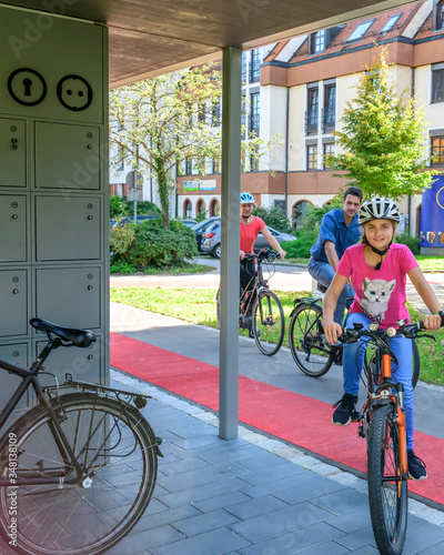 Gutgelaunte Familie nutzt ein vorbildliches Fahrrad-Abstellkonzept für einen Stadtbummel zu Fuß photo