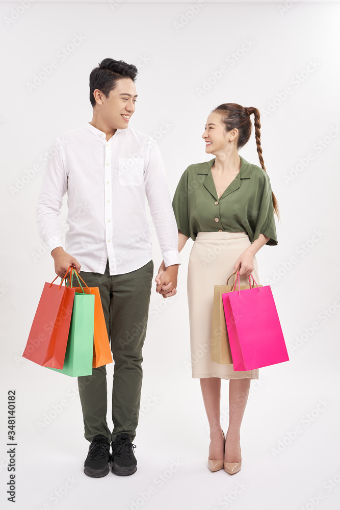 smiling couple looking at each other, holding hands and carrying shopping bags isolated on white smiling couple looking at each other, holding hands and carrying shopping bags isolated on white