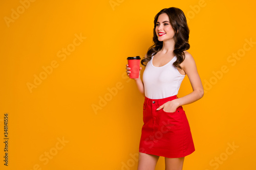 Photo of funny pretty lady hold paper cup takeaway hot coffee saturday look empty space meet friends wear casual white tank-top red skirt isolated vivid yellow color background